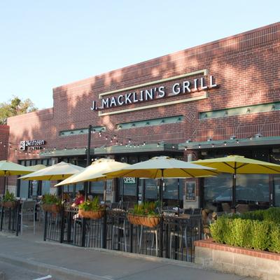Exterior with signage, outdoor seating, plants, and yellow parasols.