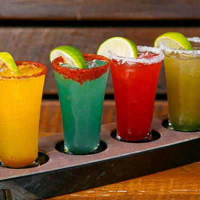 A cocktail flight of four colorful drinks.