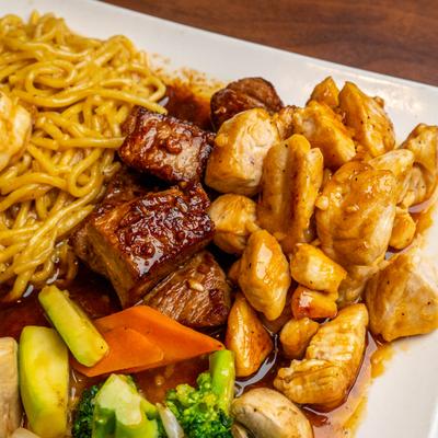 Chicken and Steak Hibachi with sides of noodles and vegetables, close-up.