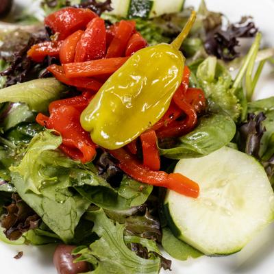 Salad with lettuce, tomatoes, cucumber, peppers, and olives.