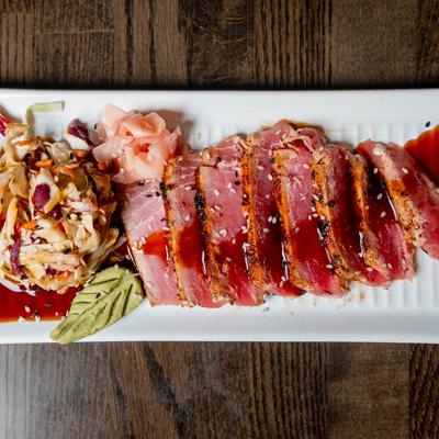 Seared tuna slices with coleslaw, pickled ginger, and soy glaze.