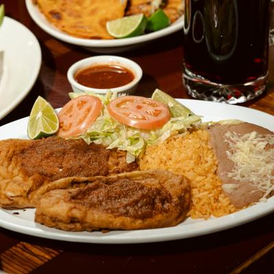 Fried fish filets served with sides of rice, beans and a salad.