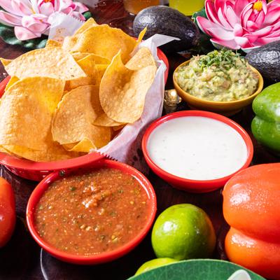 Tortilla chips with salsa, cheese dip, and guacamole.
