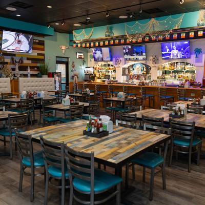 Spacious dining spaces with dining tables, booths, and a bar with multiple TV screens.