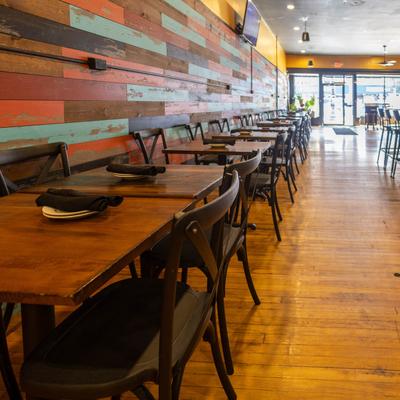 Restaurant dining area with wooden tables and colorful wood-paneled wall.