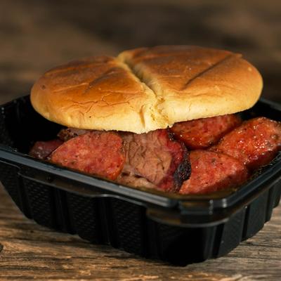 Barbecue sandwich with sausage and brisket in a takeout container.