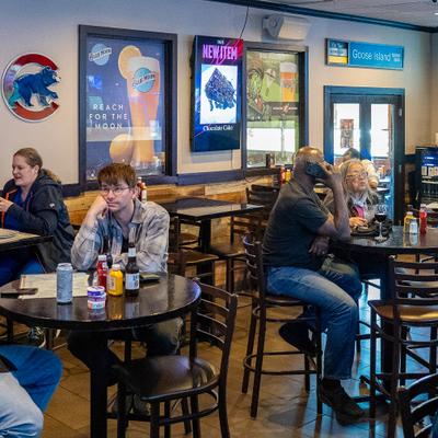 Interior with high-top table seating  decorative beer posters and guests having drinks.