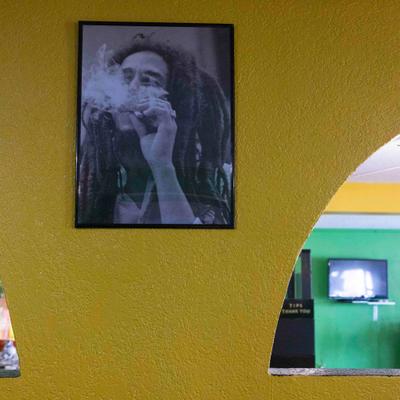 Framed picture of Bob Marley on the yelow wall.