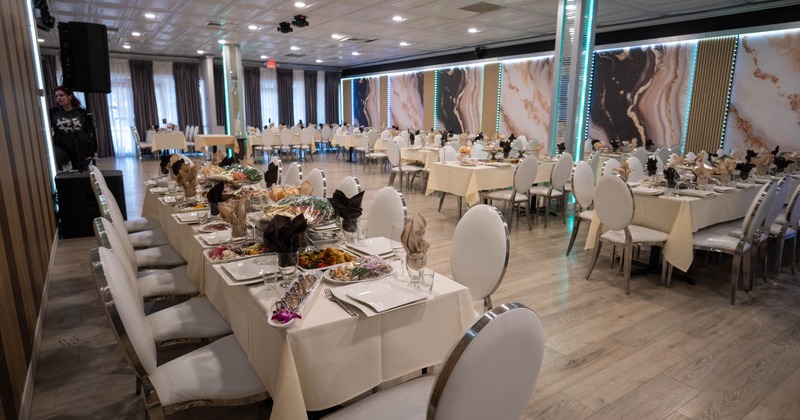 A banquet hall with set tables, abstract wall designs, and LED lights.