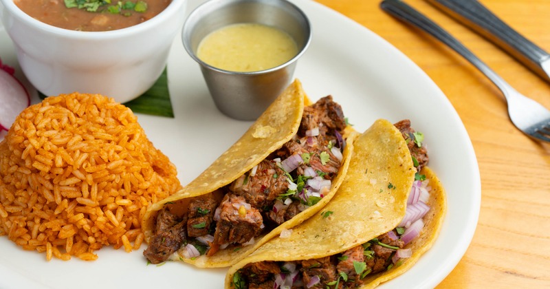 Asada Tacos served with rice, beans, pickled red onions and a dipping sauce