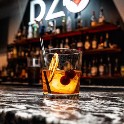 Old Fashioned cocktail garnished with dried orange wheel and cherries.