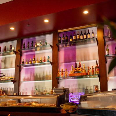 A warmly lit bar shelf displaying assorted bottles of wine and spirits.