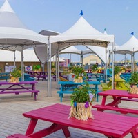 Outdoor seating area with picnic tables and frame tents.