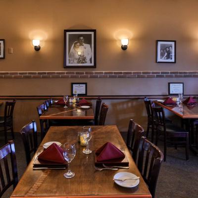 Interior with brick accents, franed pictures and dark wooden tables and chairs.