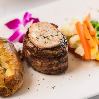 Bacon wrapped center cut filet mignon served with baled potato and veggies.