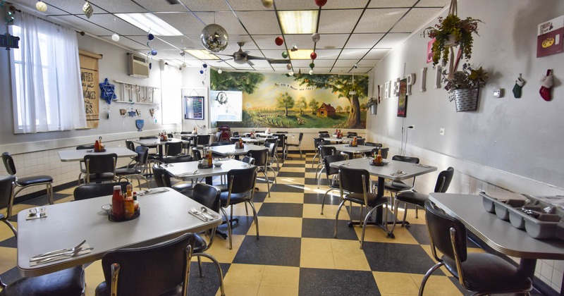 Interior, tables and chairs ready for guests, checkered tiles, various decoration