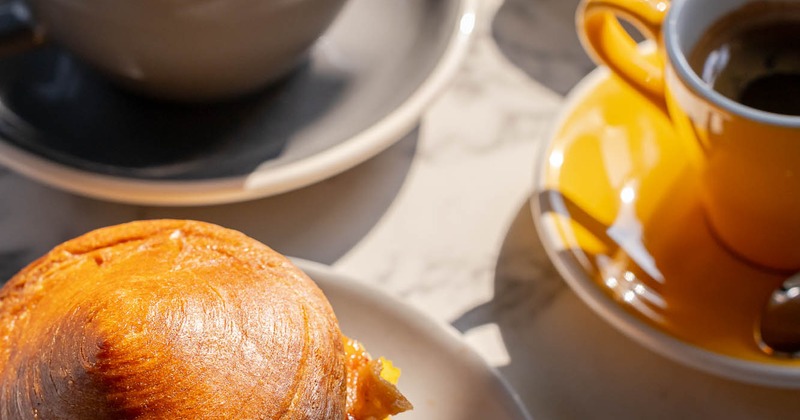 Pastry with two cups of coffee on a sunlit table