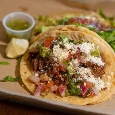Brisket tacos served with a lime wedge and salsa.
