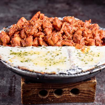 Spicy stir-fried chicken served with a side of melted cheese.