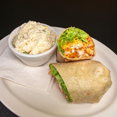 Buffalo chicken wrap sliced in half and served with a side of coleslaw.