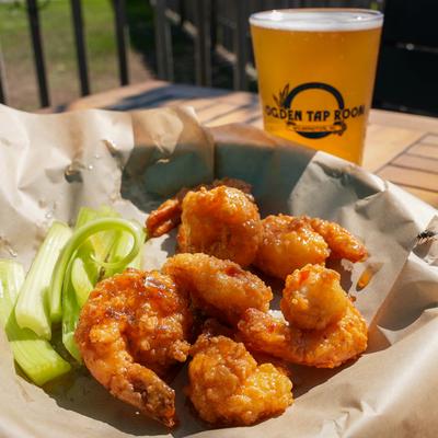 Asian fried Shrimp served with celery sticks and a glass of beer.