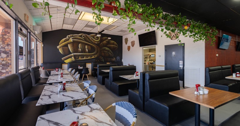 Covered seating area with single and double leather booths and marble tables