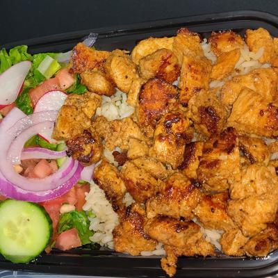 Grilled chicken over rice with a side salad of lettuce, cucumbers, radishes, and red onions.