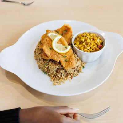 Fried fish served with dirty rice and corn.