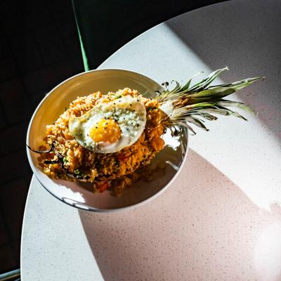 Pineapple Fried Rice served in a hollowed-out pineapple half, topped with fried egg.