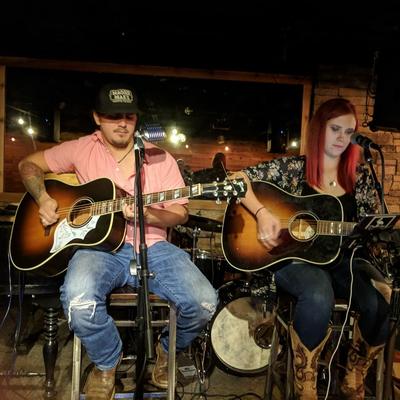Guitar duo performing on a stage.