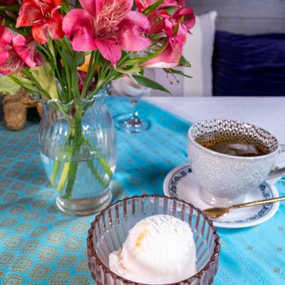 Coconut ice cream served alongside a cup of tea and a vase of flowers.