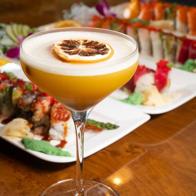 Happy Ending cocktail with food plates in the background.