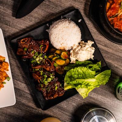 Korean BBQ meal featuring beef short ribs, rice, potato salad, cucumber kimchi and lettuce.