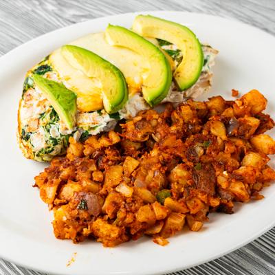 Grandmother Benedict topped with hollandaise sauce and avocado, served with home fries.