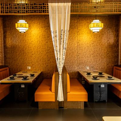Interior featuring booths with orange seating divided by a patterned curtain.