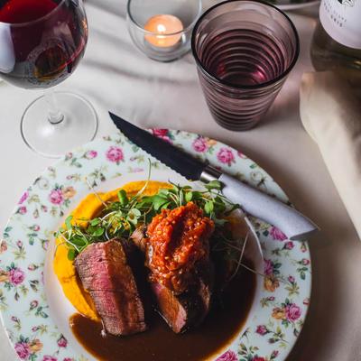 Steak dish accompanied with red wine.