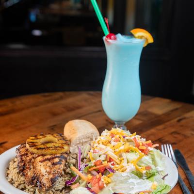 Chicken breast dinner served with a Blue Hawaiian cocktail.