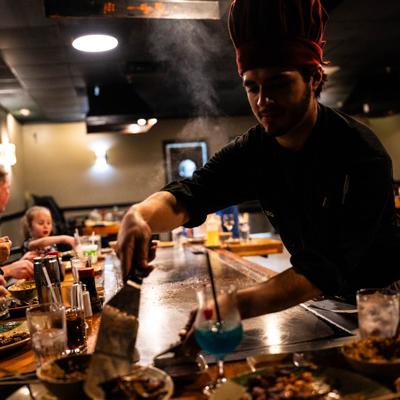 A chef skillfully serves food prepared on a teppanyaki grill.