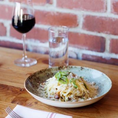 Spaghetti Carbonara served on the table with glasses of red wine and water.