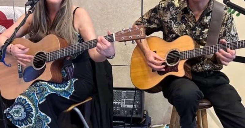 Two musicians with acoustic guitars during live music performance