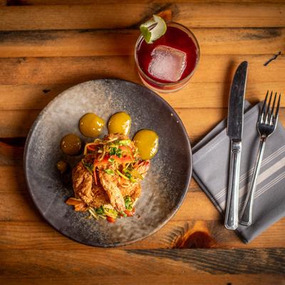 Coconut shrimp dish served on a gray plate, accompanied with a red cocktail.