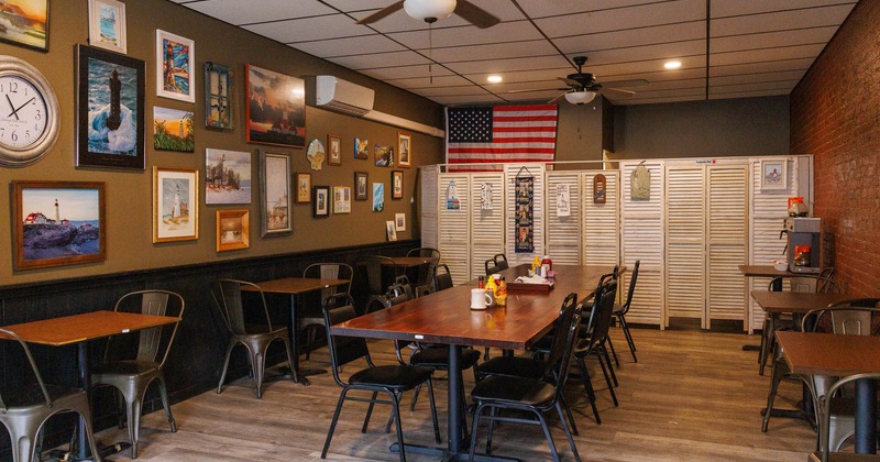 Dining area with a long table, framed pictures on the wall, and an American flag