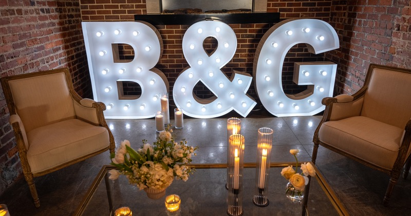 Small brick walled side room for the bride and groom to sit.  Large LED lit letters B&G