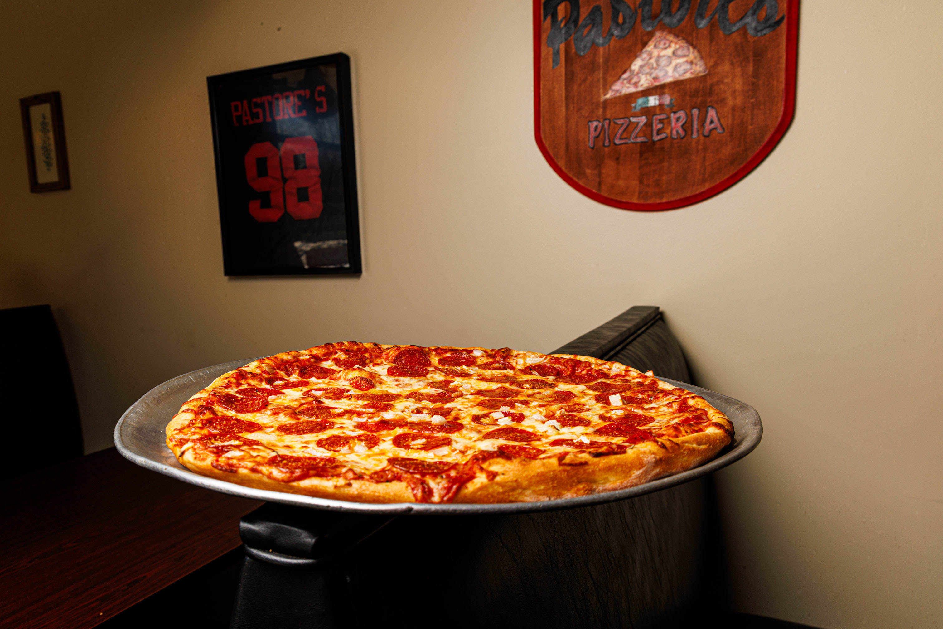 Pepperoni pizza served on a tray, beside wall signs