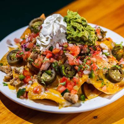 Nachos, with pico de gallo, sour cream, beans, pickled jalapenos, and cheddar cheese.