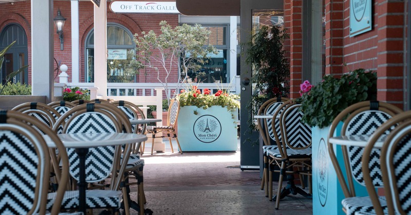 Outdoor seating area -  chevron-patterned chairs and tables, leading to a street view with shops.