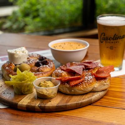 Bavarian pretzel charcuterie board with cured meats, pickles, mustard, and beer cheese.