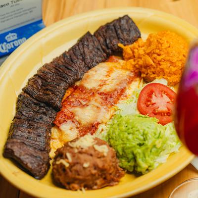 Steak and enchilada platter with beans, rice, and guacamole.