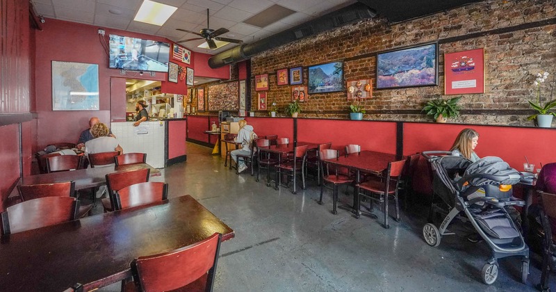 Interior, tables, chairs, eating customers, brick wall with framed paintings, wall TV