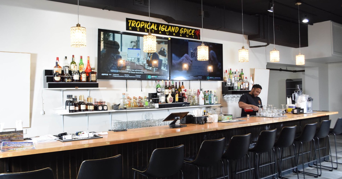 Interior, bar area, wooden top bar with stools, shelves with drinks, TVs on the wall